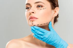 plastic surgeon touching face of attractive woman with marked face 300x200 1